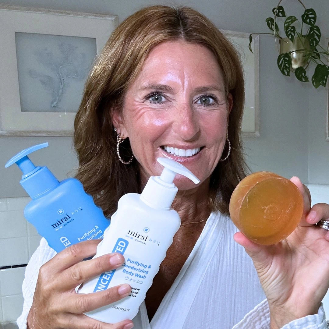 Smiling woman holding Mirai Clinical Purifying and Deodorizing Set with persimmon soap, body wash, and shampoo, designed to fight nonenal aging odor naturally.