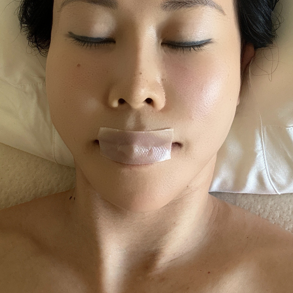 Individual using Mirai Clinical's Sleep Tape, positioned across the nose and mouth, aiding in optimal breathing for a restful night's sleep.