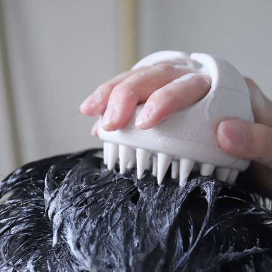 Close-up of Mirai Clinical Scalp Massager in use, lathering shampoo into hair with silicone bristles.