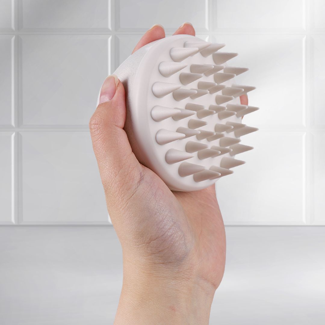 Side view of Mirai Clinical Scalp Massager held in hand, showcasing its ergonomic design and soft silicone bristles.