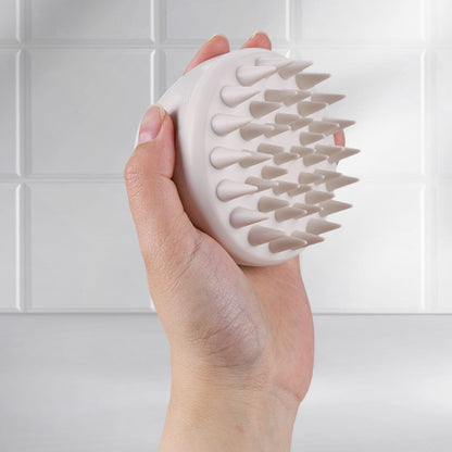 Side view of Mirai Clinical Scalp Massager held in hand, showcasing its ergonomic design and soft silicone bristles.