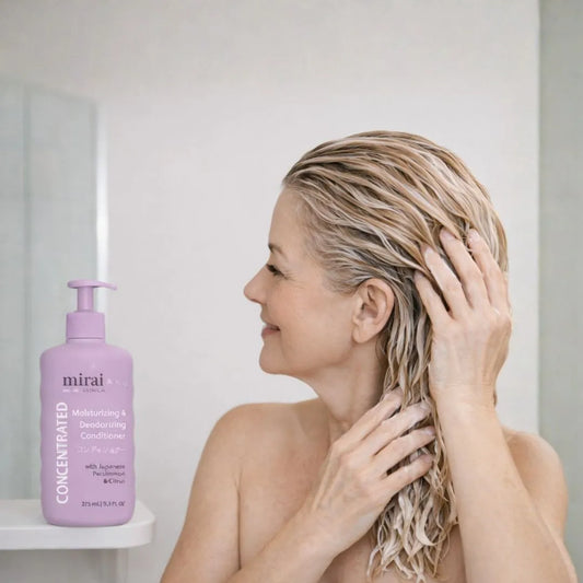 Woman using Mirai Clinical persimmon moisturizing deodorizing conditioner to support scalp hygiene and help reduce nonenal aging body odor.