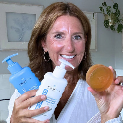 Smiling woman holding Mirai Clinical Purifying and Deodorizing Set with persimmon soap, body wash, and shampoo, designed to fight nonenal aging odor naturally.