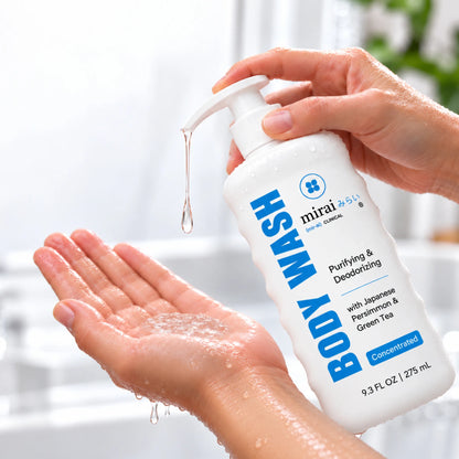 Wet hands pumping Mirai Clinical Purifying & Deodorizing Body Wash with Japanese Persimmon & Green Tea, a concentrated 9.3 fl oz formula, into an open palm in a bright bathroom.