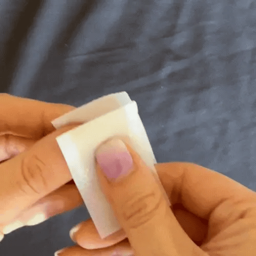 Animated GIF of a woman expertly tearing Koko Face Yoga's Sleep Tape, also referred to as mouth tape, before application, highlighting the proper method for optimal nighttime comfort.