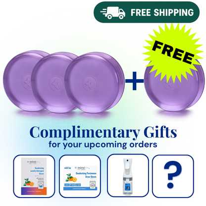 Promotional graphic showing four purple round bars of soap plus a yellow starburst that says FREE, with a green 'FREE SHIPPING' banner at the top and text reading 'Complimentary Gifts for your upcoming orders.' Four small product preview cards appear along the bottom, including a spray bottle and a question mark representing included gifts.

