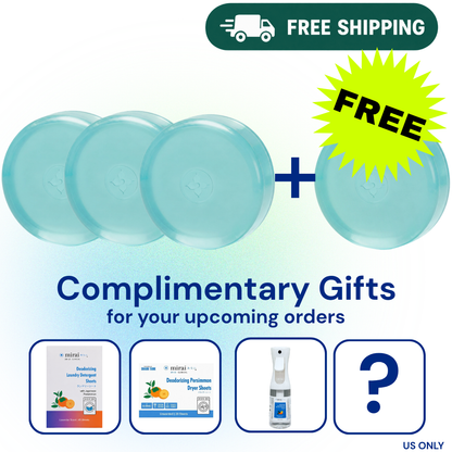 Promotional graphic showing four round light blue bath towels with a plus sign and a yellow starburst reading FREE, above the text 'Complimentary Gifts for your upcoming orders.' Four small product preview boxes below show sample gift items, including a laundry product, dryer sheets, a spray bottle, and a question mark.