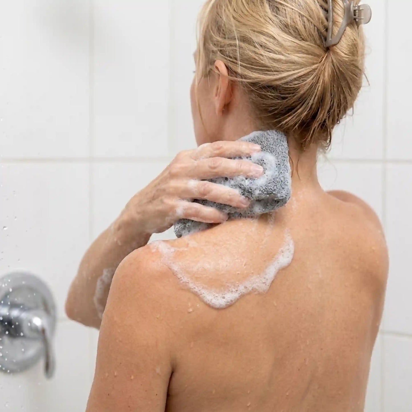 Woman using the Mirai Clinical soap saver bag to wash the back of her neck, targeting a nonenal odor hotspot