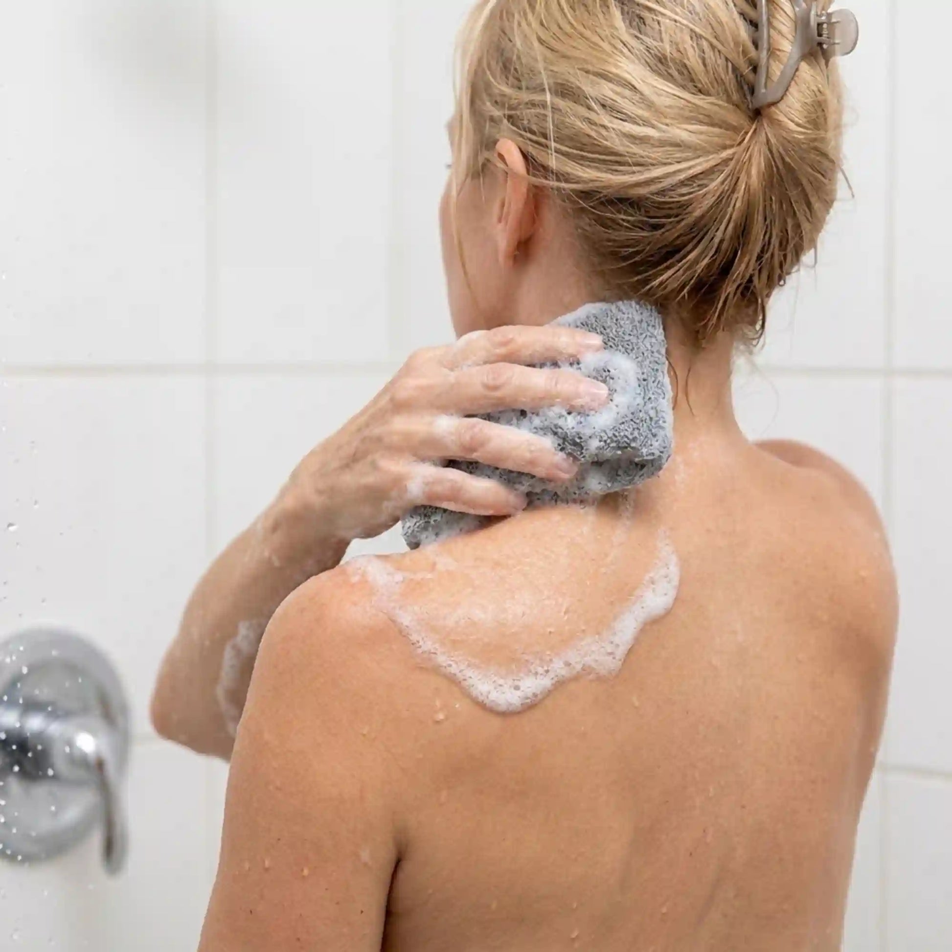 Woman using the Mirai Clinical soap saver bag to wash the back of her neck, targeting a nonenal odor hotspot