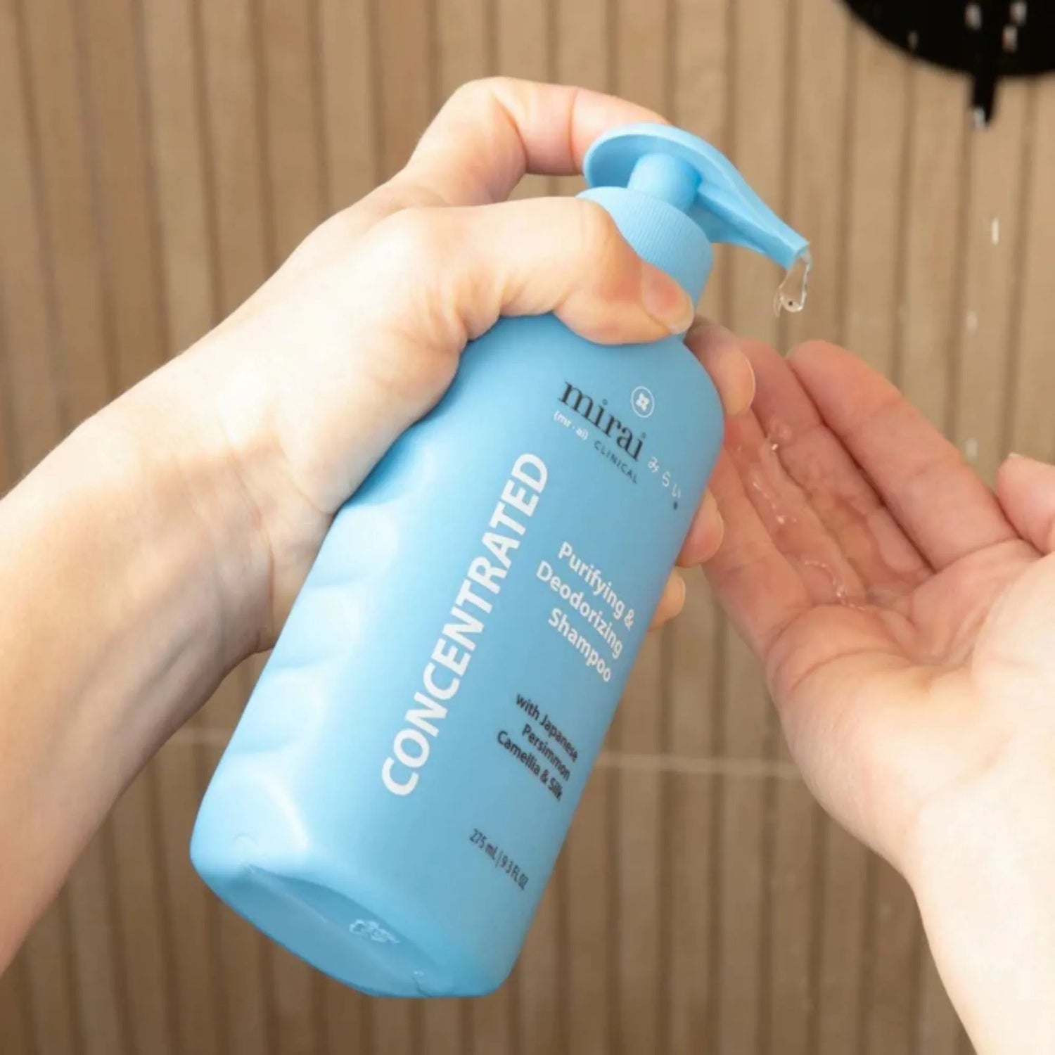 Hands pumping Mirai Clinical Concentrated Deodorizing Shampoo in the shower