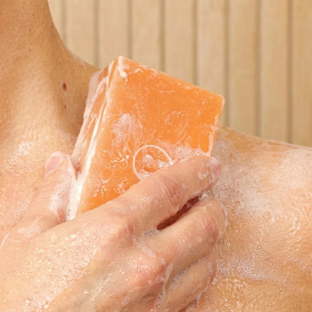 Person lathering Mirai Clinical Purifying and Deodorizing soap bar on shoulder and back in shower