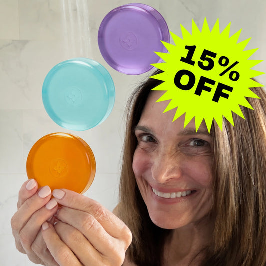 Woman holding 3 Mirai Clinical Nonenal soap bars — Lavender (purple), Mint (mint), and Regular (orange) — with 15% off promotional badge