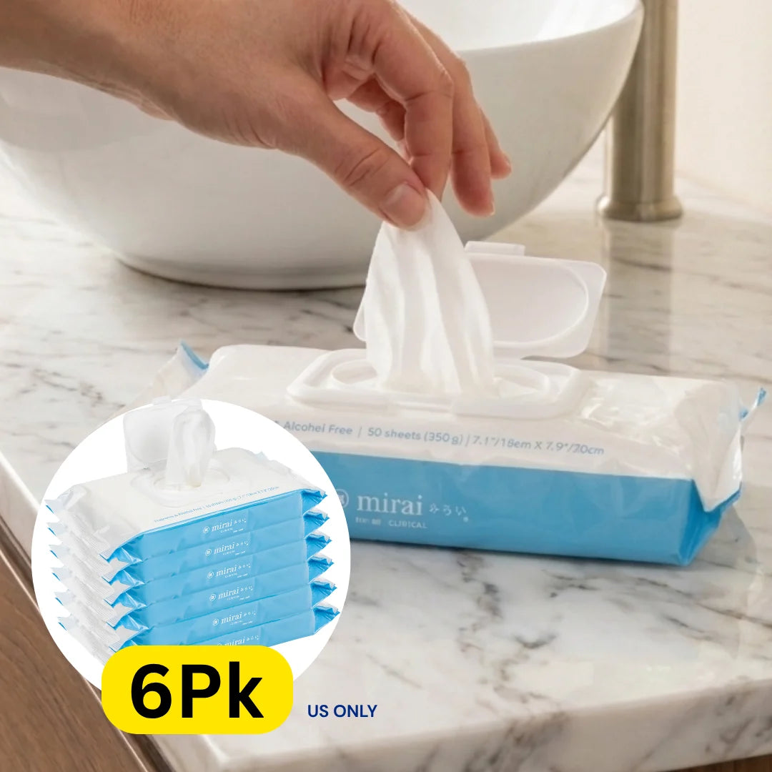 Hand reaching for a Mirai Clinical Persimmon body cleaning wipe from a pack on a marble countertop.