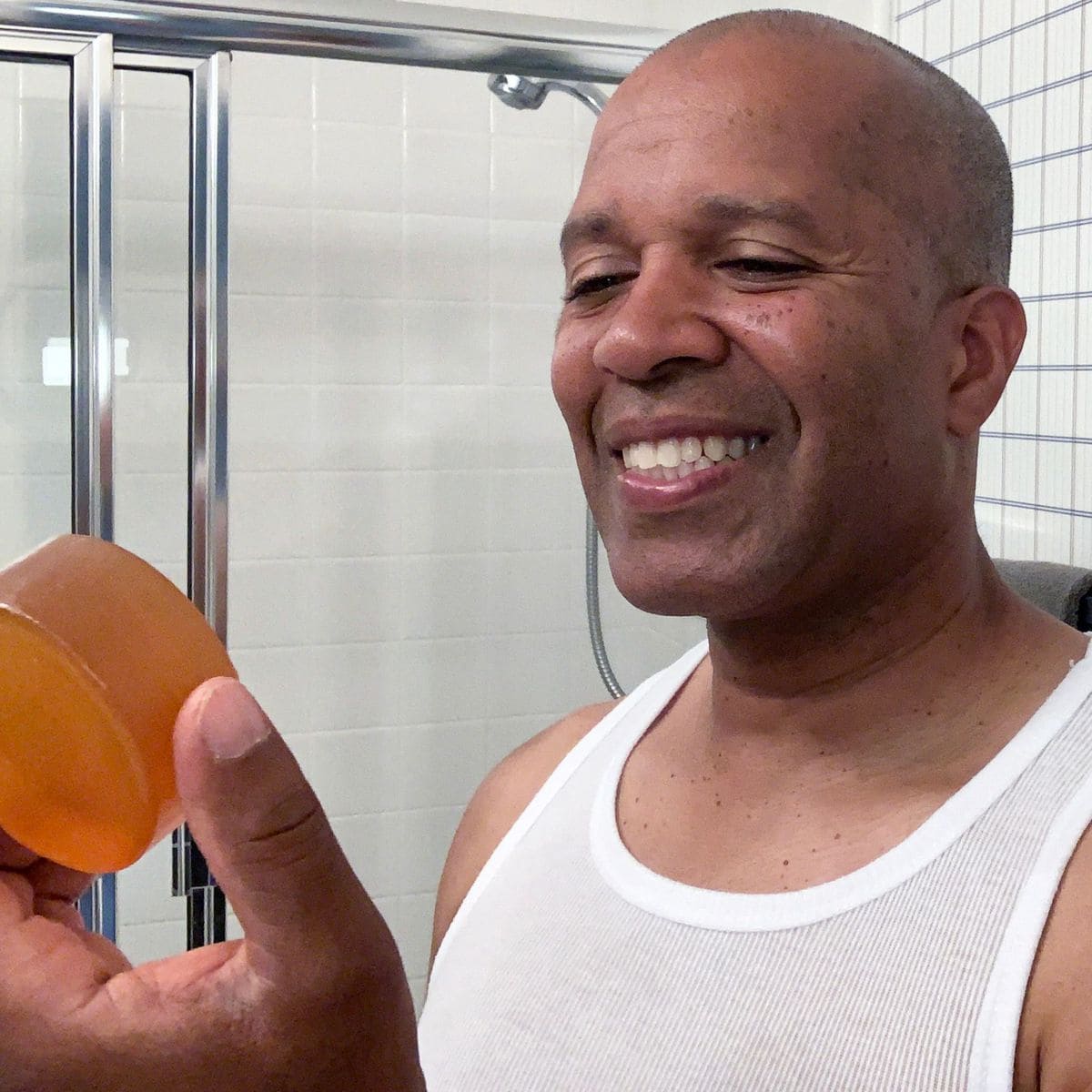 Image of a content customer holding a bar of soap infused with persimmon, specifically designed for deodorizing and neutralizing nonenal-related body odor.